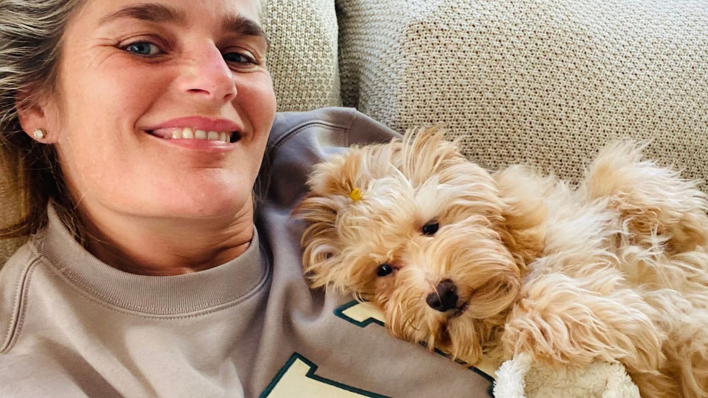 Angelique met een jonge hond tegen haar schouder