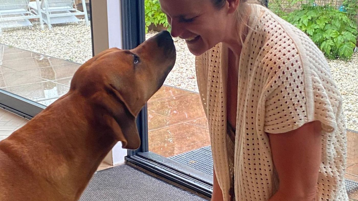 Grote hond rustig neus aan neus met Angelique in de deuropening
