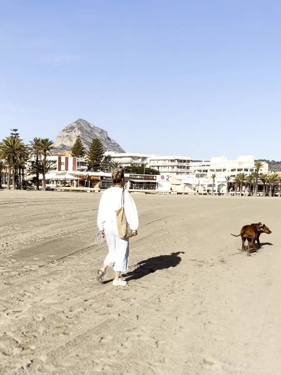 Angelique loopt met twee honden over het strand van Jávea, met de Montgó op de achtergrond
